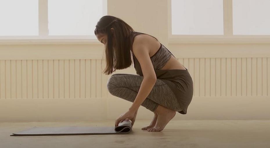 A woman rolling up a yoga mat.